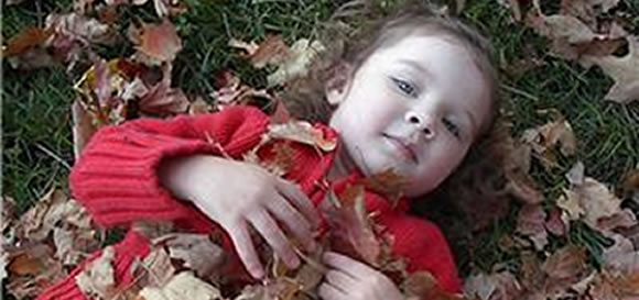 Picture of girl lying in the leaves and link to Homepage